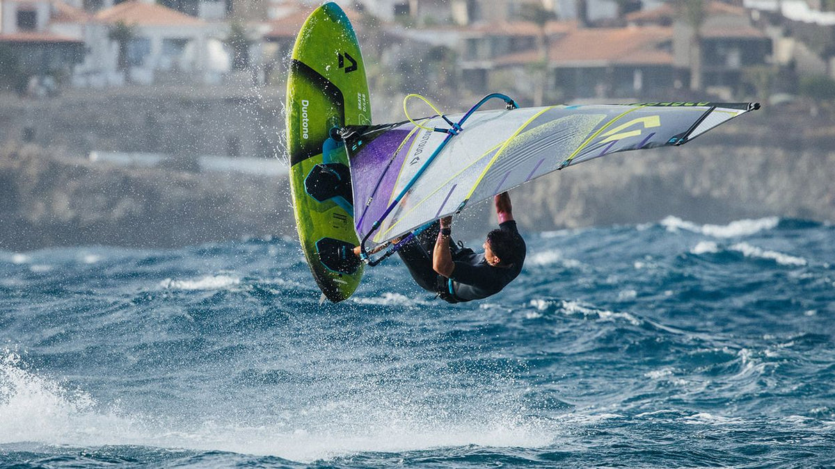 Duotone Skate D/LAB Kiteboard in Grün und Blau mit Segel beim Freestyle-Trick im Wasser