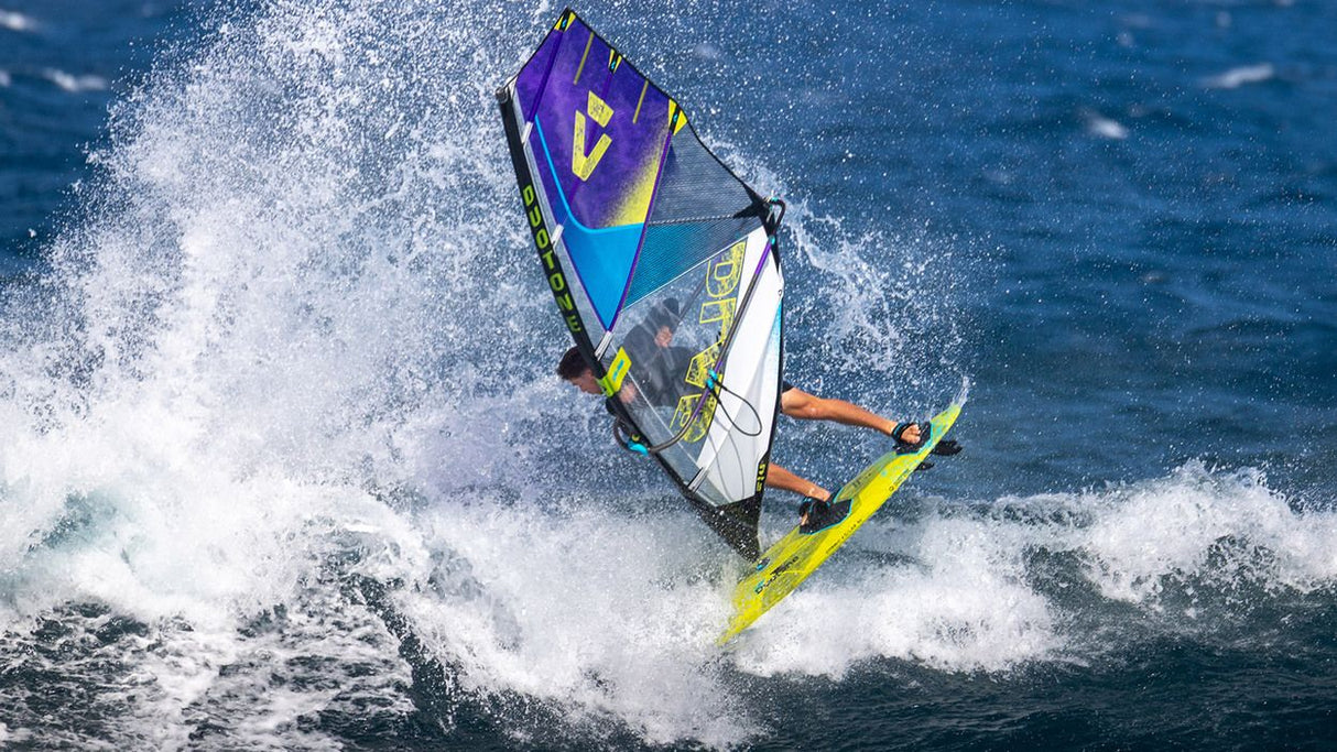 Duotone Super_Hero D/LAB 2027 Windsurfboard in Violett, Blau und Gelb auf dem Wasser mit Wellen, Draufsicht