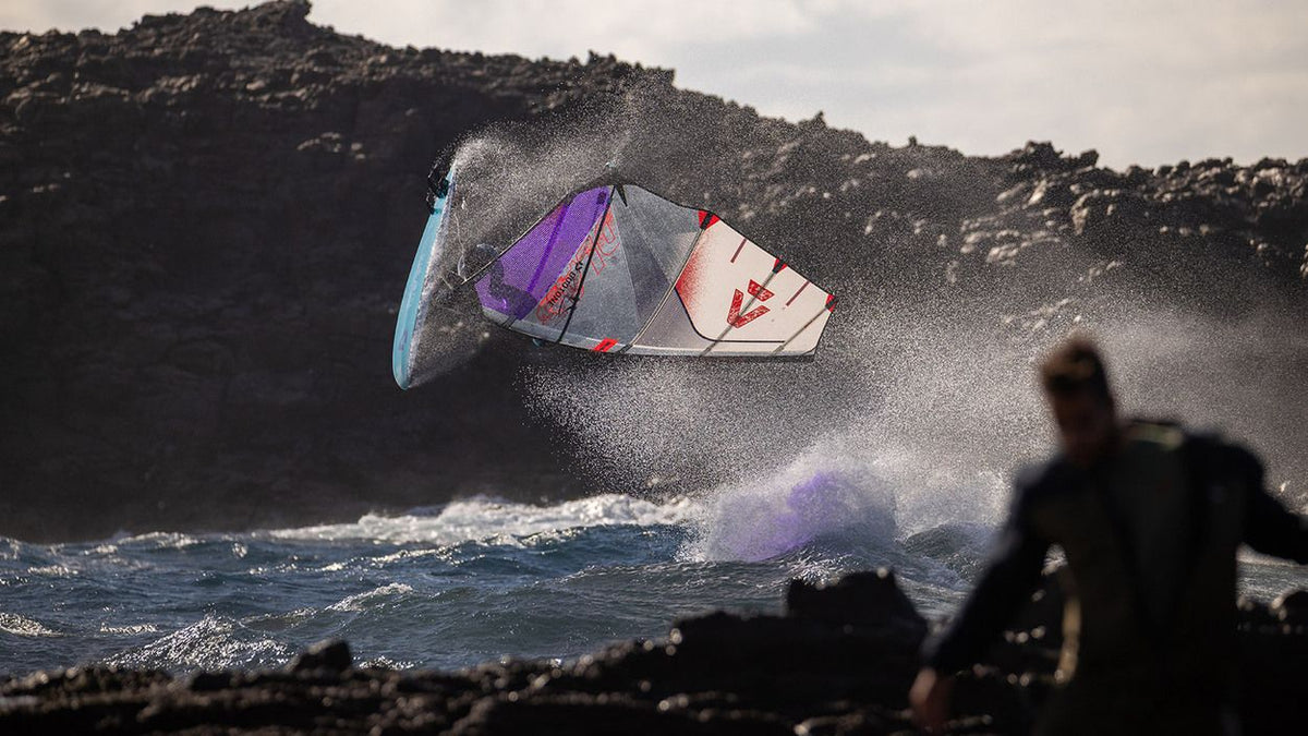 Duotone Super_Hero D/LAB 2027 Kite in Lila und Hellblau beim Kitesurfen über Wellen, Action-Perspektive