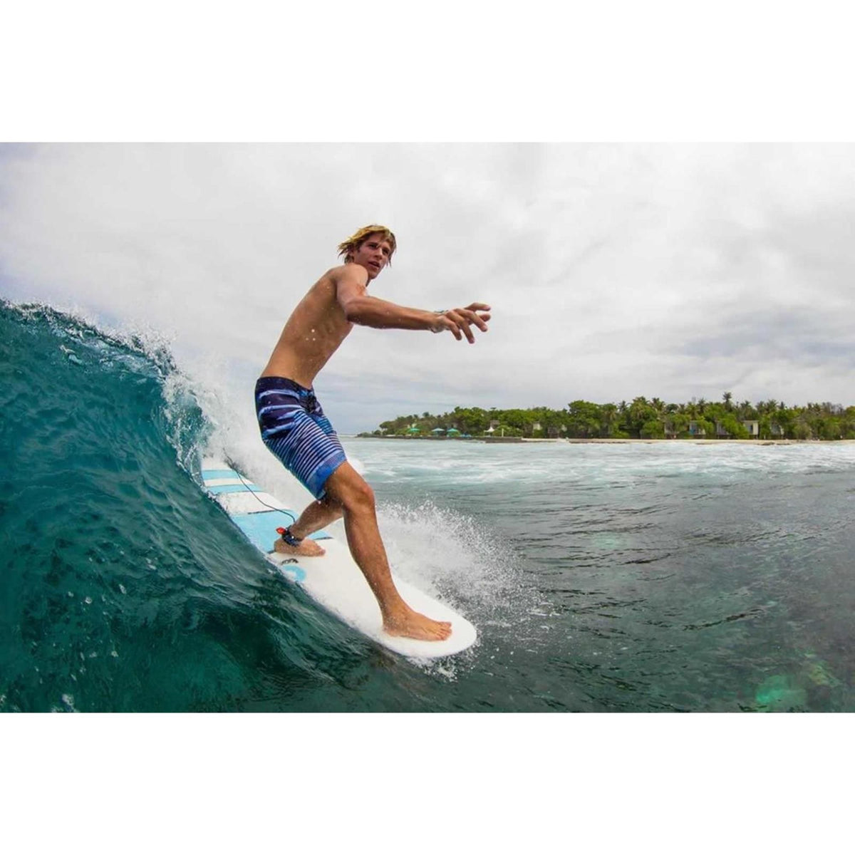 Surfer reitet Welle auf weißem Torq TET Longboard, Seitenansicht im Meer
