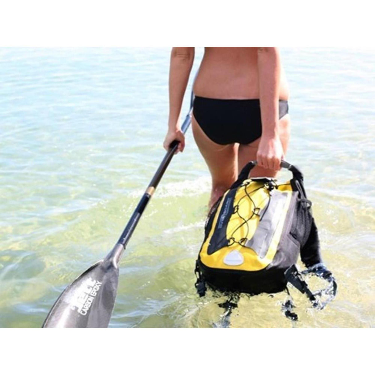 OverBoard Classic 20 Liter wasserdichter Rucksack in Schwarz-Gelb, von Person am Strand getragen
