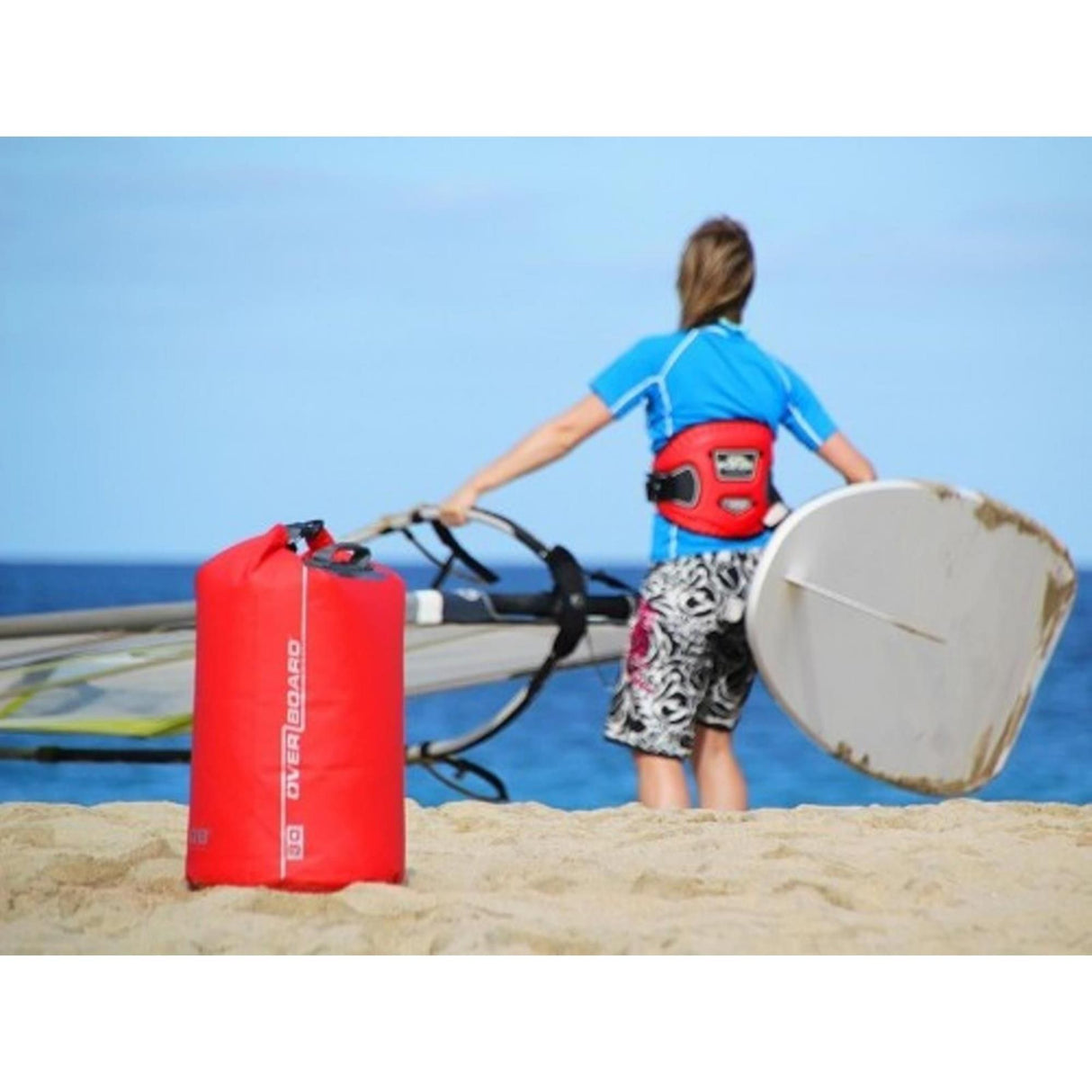 OverBoard wasserdichter Packsack 30 Liter rot, am Strand neben Kitesurfing-Equipment, Lifestyle-Ansicht