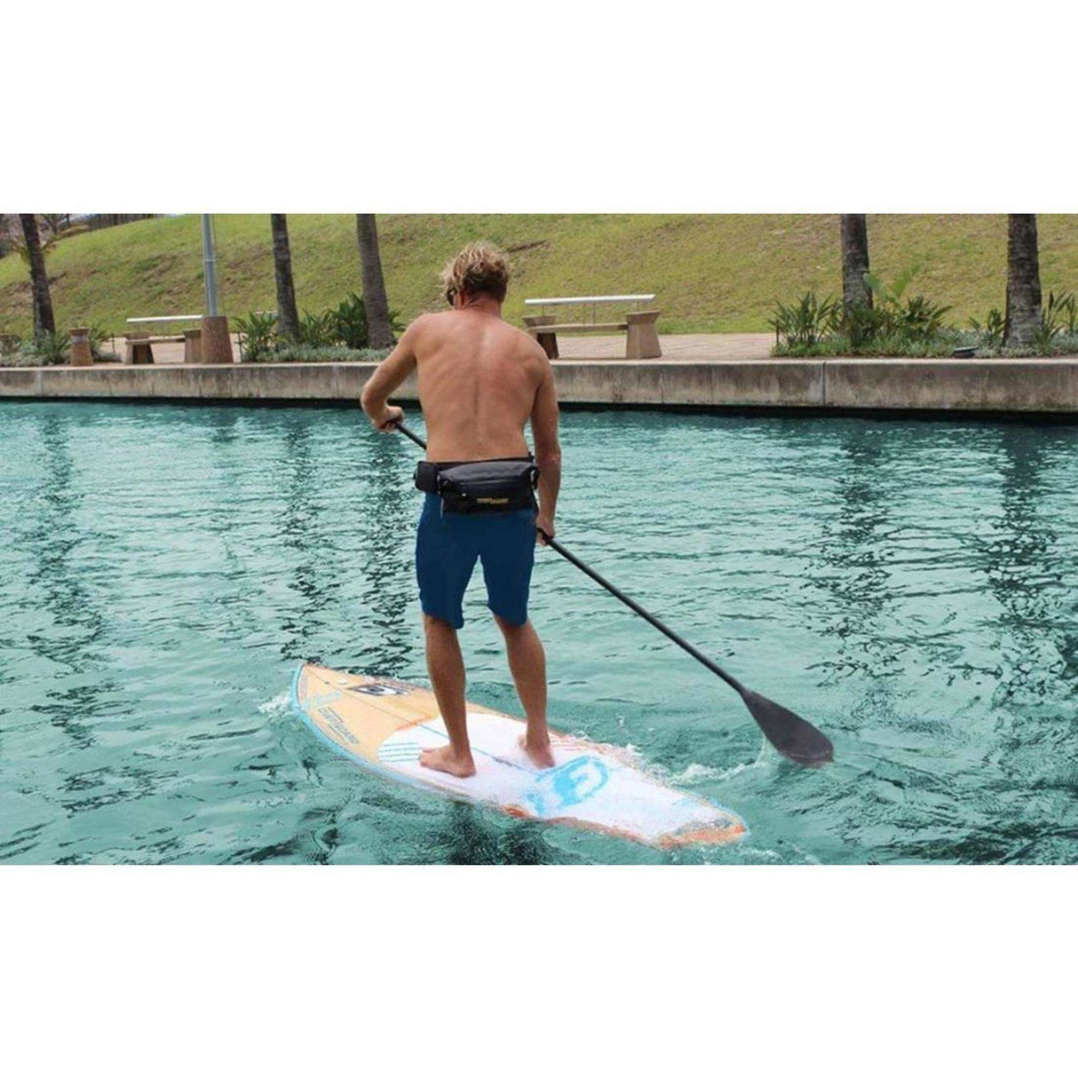 OverBoard wasserdichte Hüfttasche LIGHT in Schwarz, getragen beim Stand-up Paddleboarding im Wasser