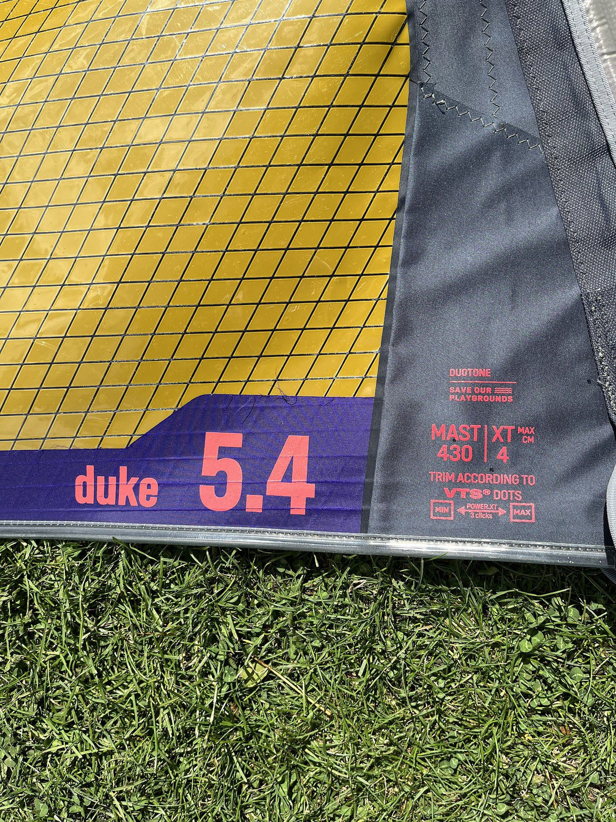 Duotone Duke 5.4 Kite gelb-blau mit Mastband auf Gras, Detailansicht des Segels und der Beschriftung