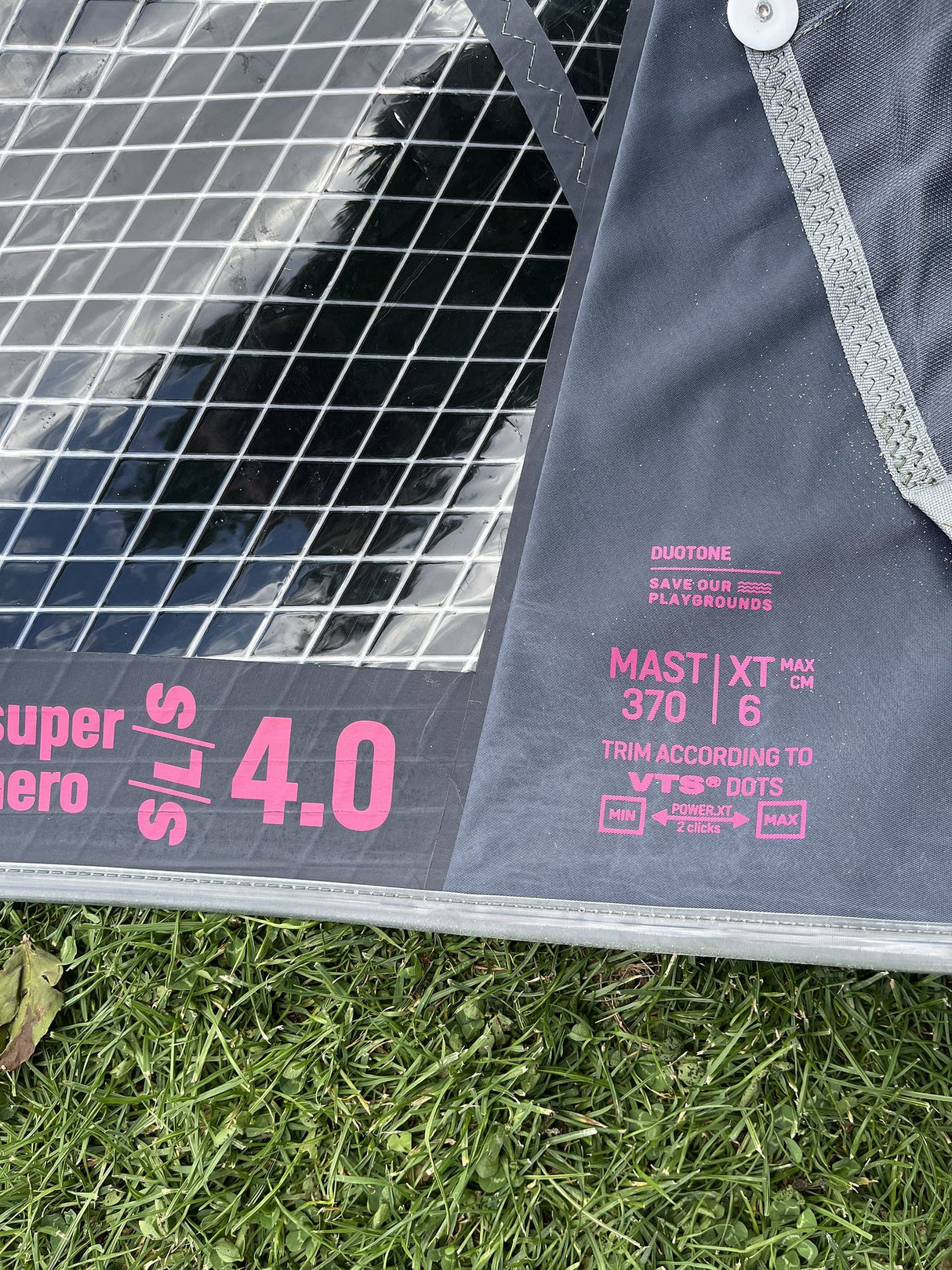 Duotone Super Hero SLS 4 2026 Kite mit Duotone-Branding in Grau und Pink, Detailansicht des Segels auf Rasen