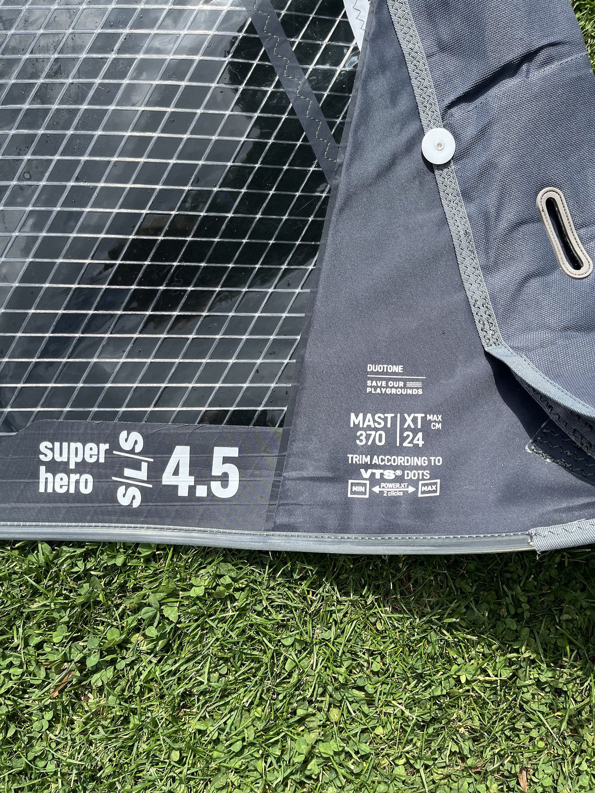 Duotone Super Hero SLS 4.5 Kiteboard grau-schwarz mit Netzstruktur, Detailansicht auf Gras