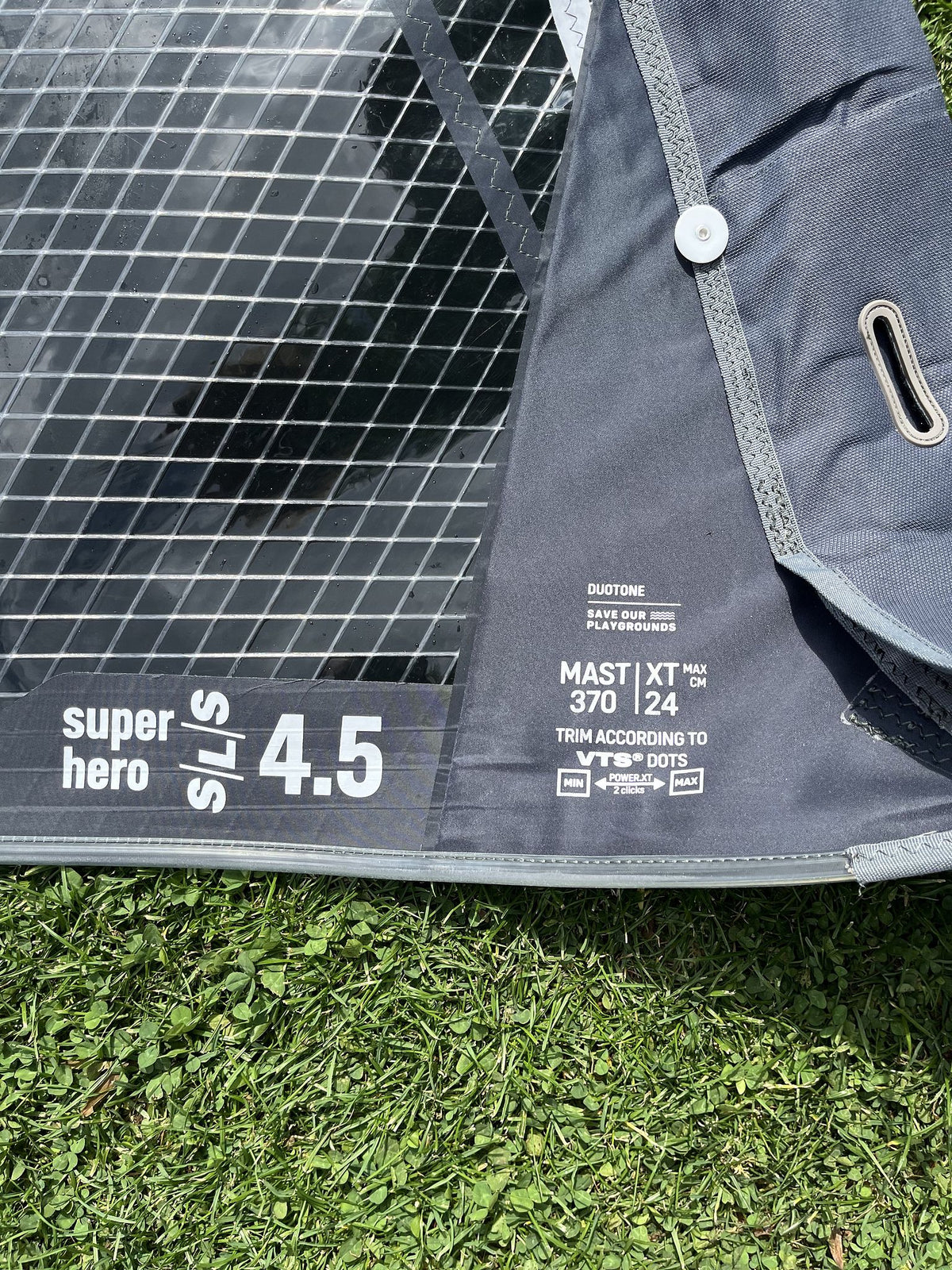 Duotone Super Hero SLS 4.5 Kiteboard grau-schwarz mit Netzstruktur, Detailansicht auf Gras
