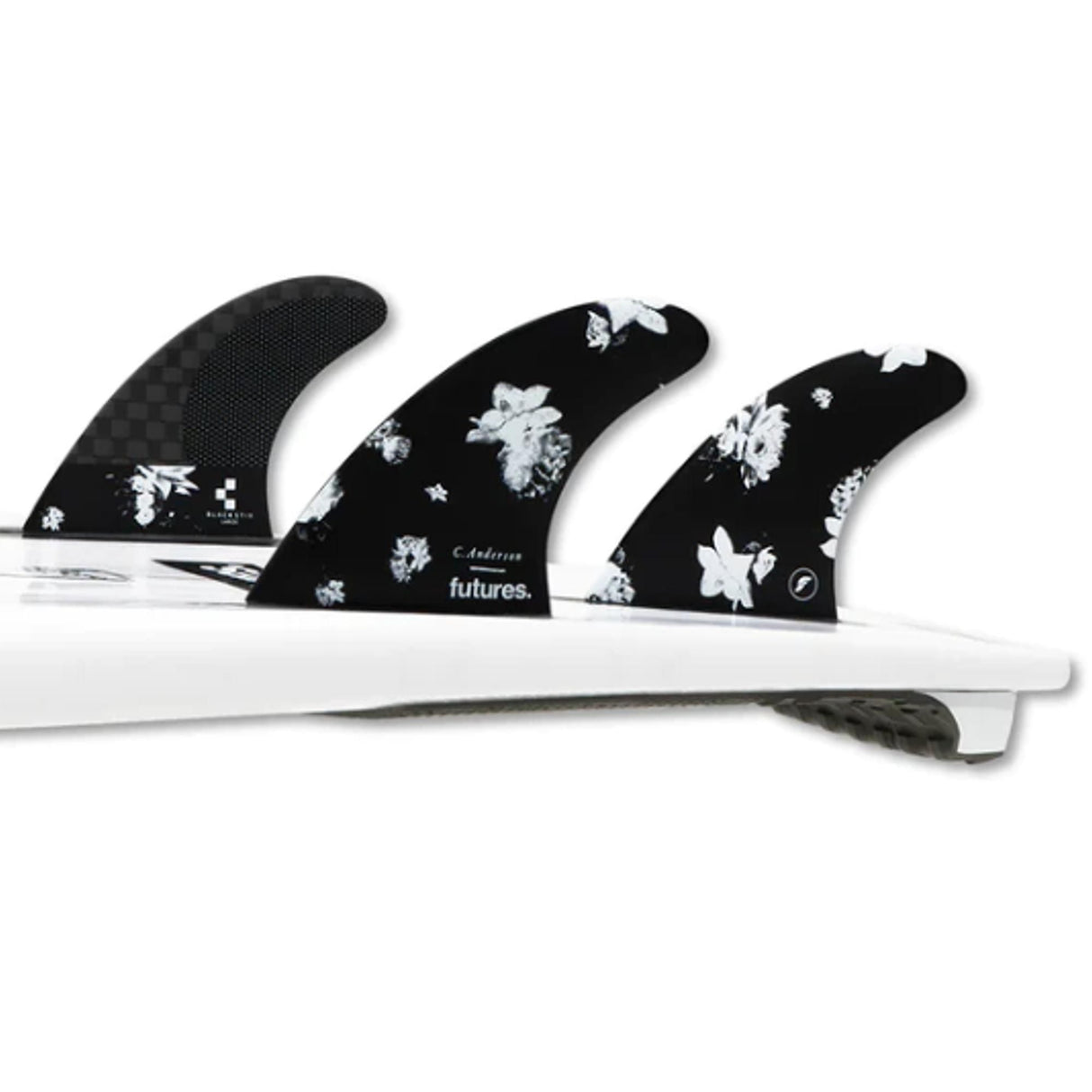 Futures Thruster Fin Set Ando Blackstix, drei schwarze Flossen mit weißem Blumenmuster auf weißem Surfboard, Draufsicht