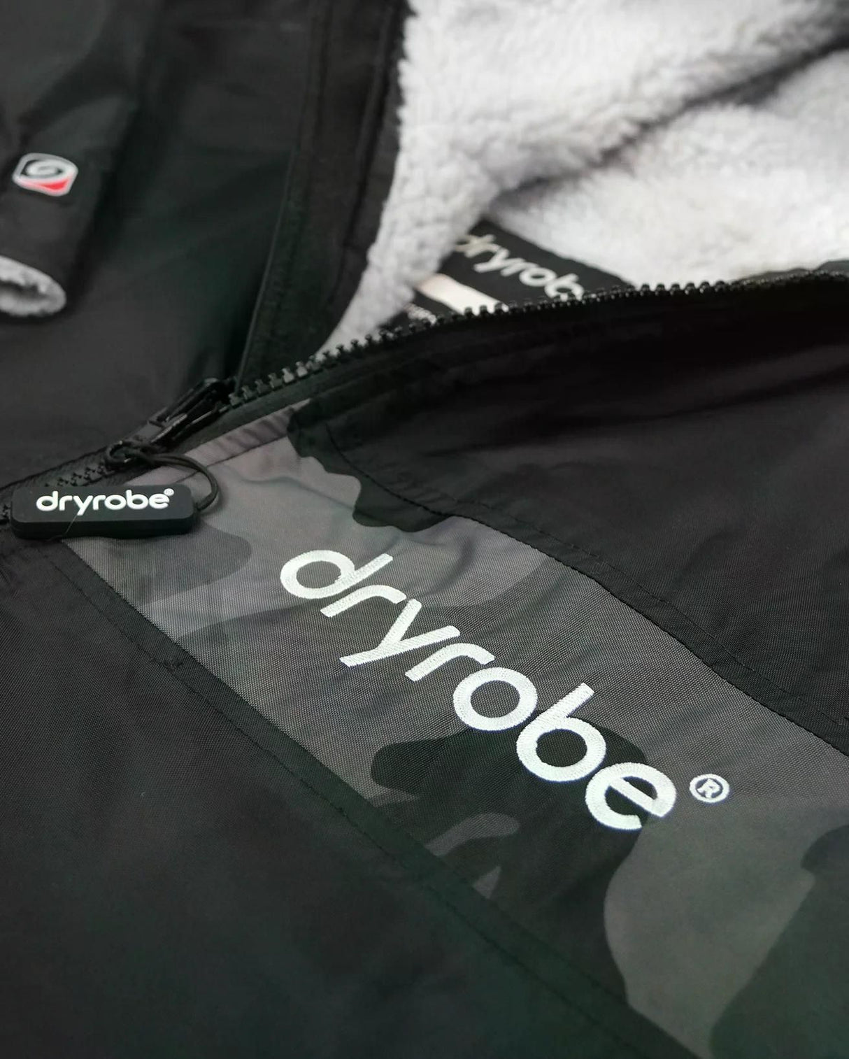 DRYROBE Advance Kurzarm in Schwarz mit weißem Fleece-Futter, Detailansicht des Reißverschlusses und Logo