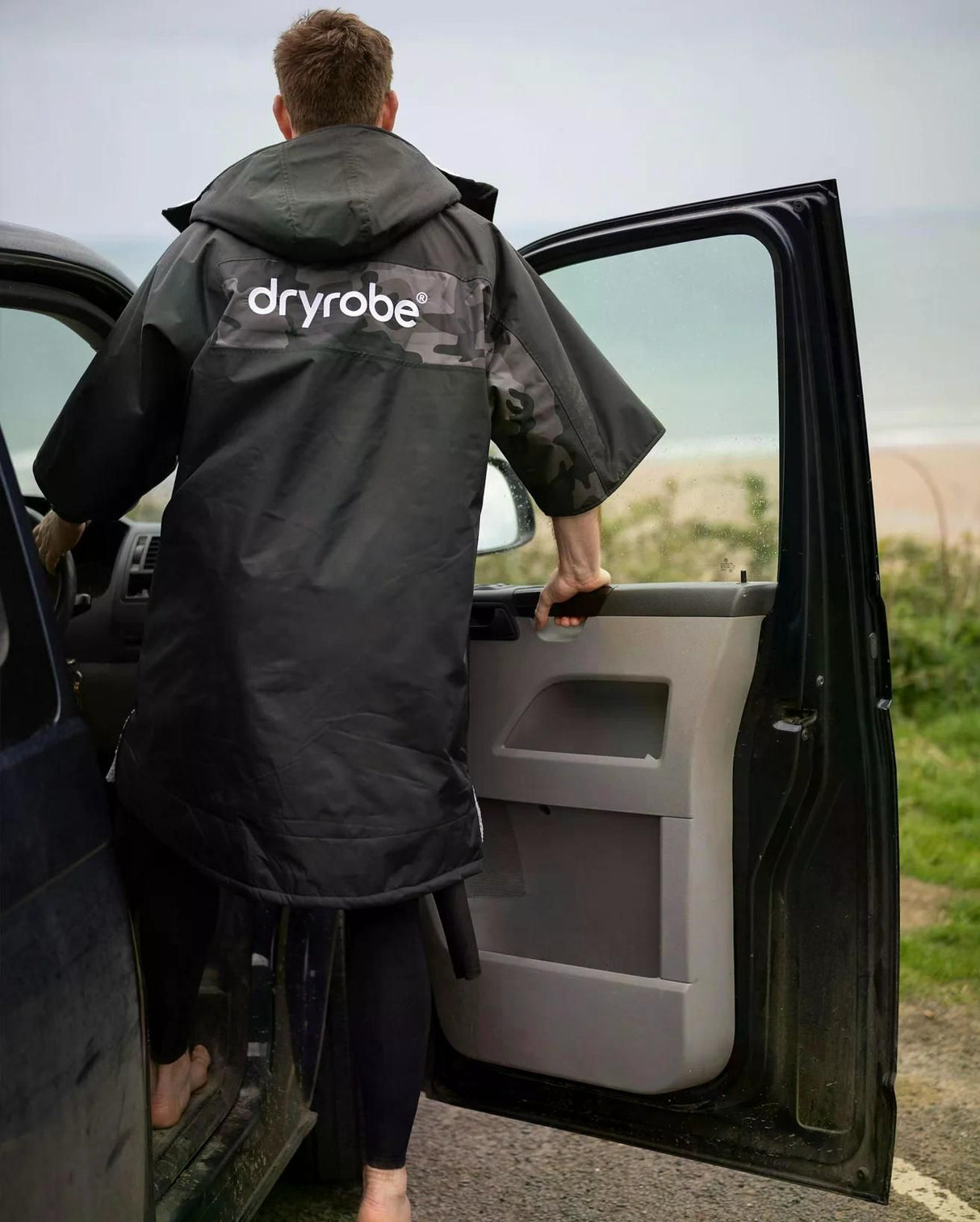 DRYROBE Advance Kurzarm in Schwarz, Rückansicht, Person trägt Robe neben Auto