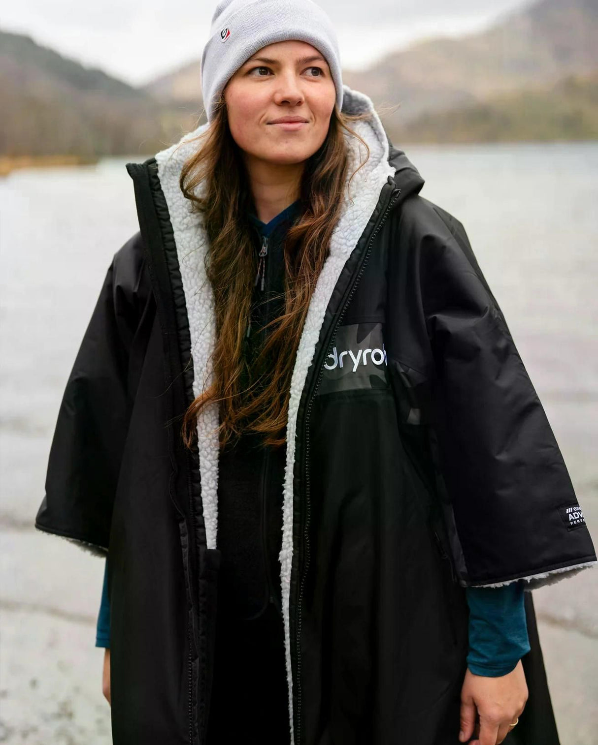 DRYROBE Advance Kurzarm schwarzer Umhang mit Sherpa-Futter, Frontansicht an einem See getragen