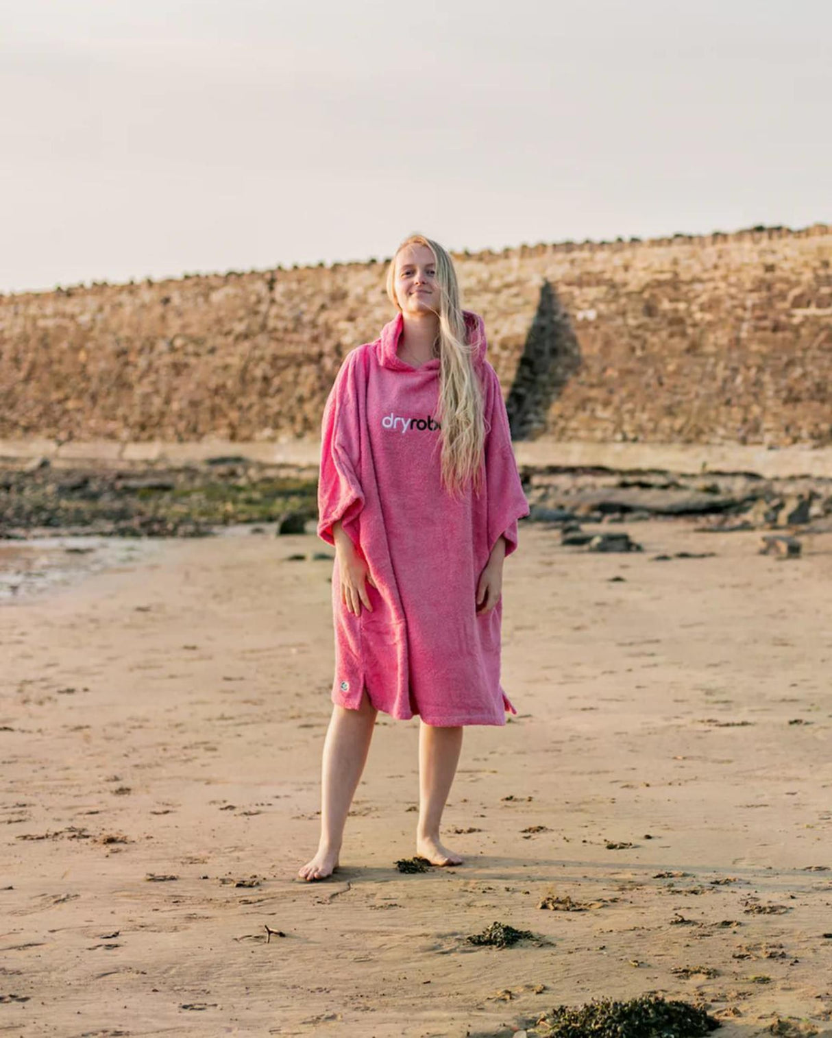 Dryrobe Handtuchmantel aus Bio-Baumwolle in Pink, getragen am Strand, Vorderansicht