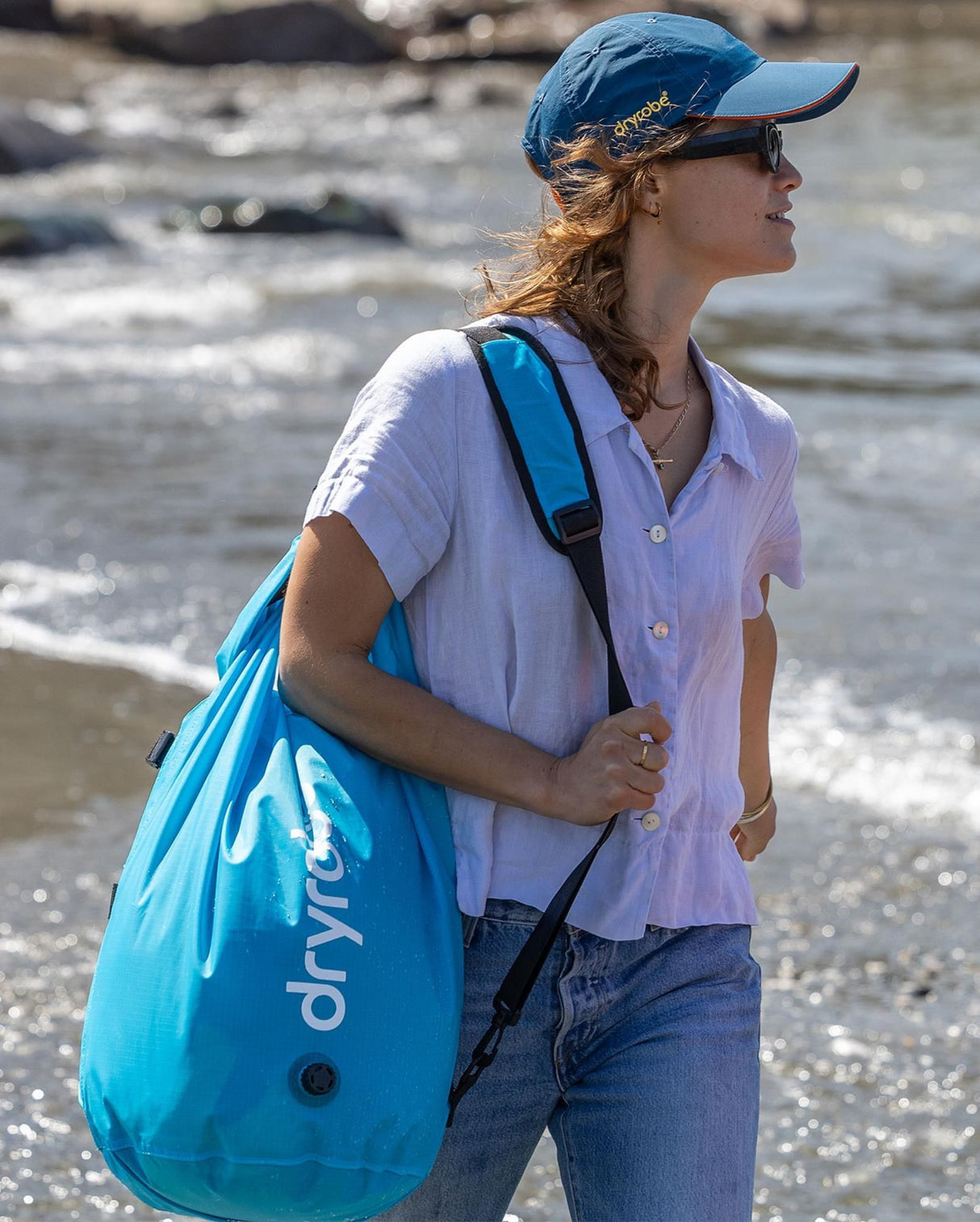 Dryrobe Drybag wasserdichter Packsack in Blau, über der Schulter getragen am Strand