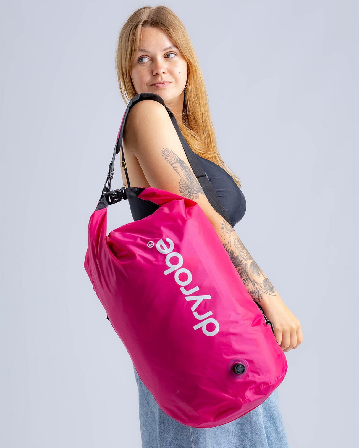Dryrobe Drybag wasserdichter Packsack in Pink, von Frau über der Schulter getragen, mit Dryrobe-Logo und Tragegriffen
