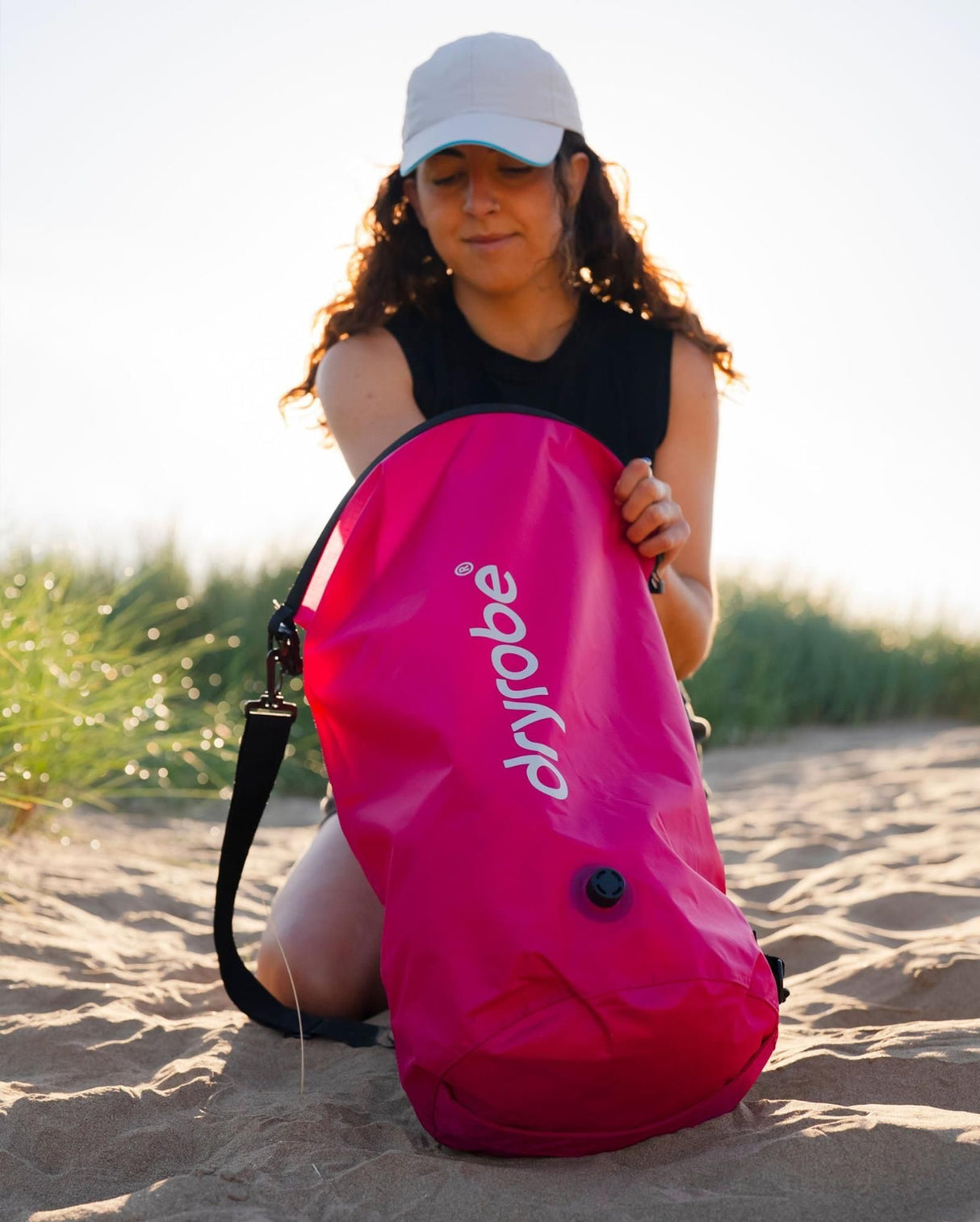 Dryrobe wasserdichter Packsack Drybag in Pink, von Person am Strand gehalten, mit Schultergurt und Dryrobe-Branding