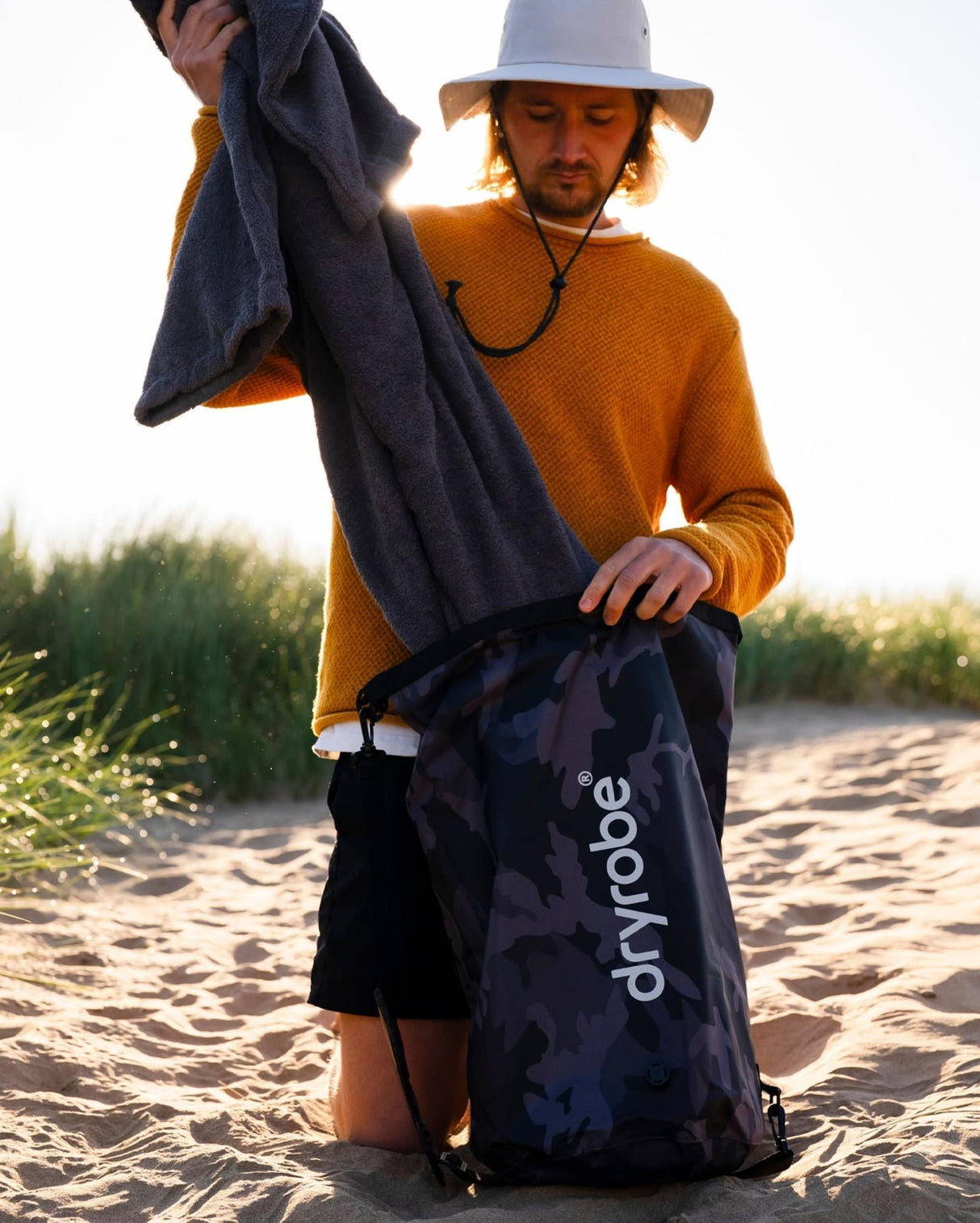 Dryrobe wasserdichter Packsack Drybag in Dunkelblau, von Mann am Strand präsentiert