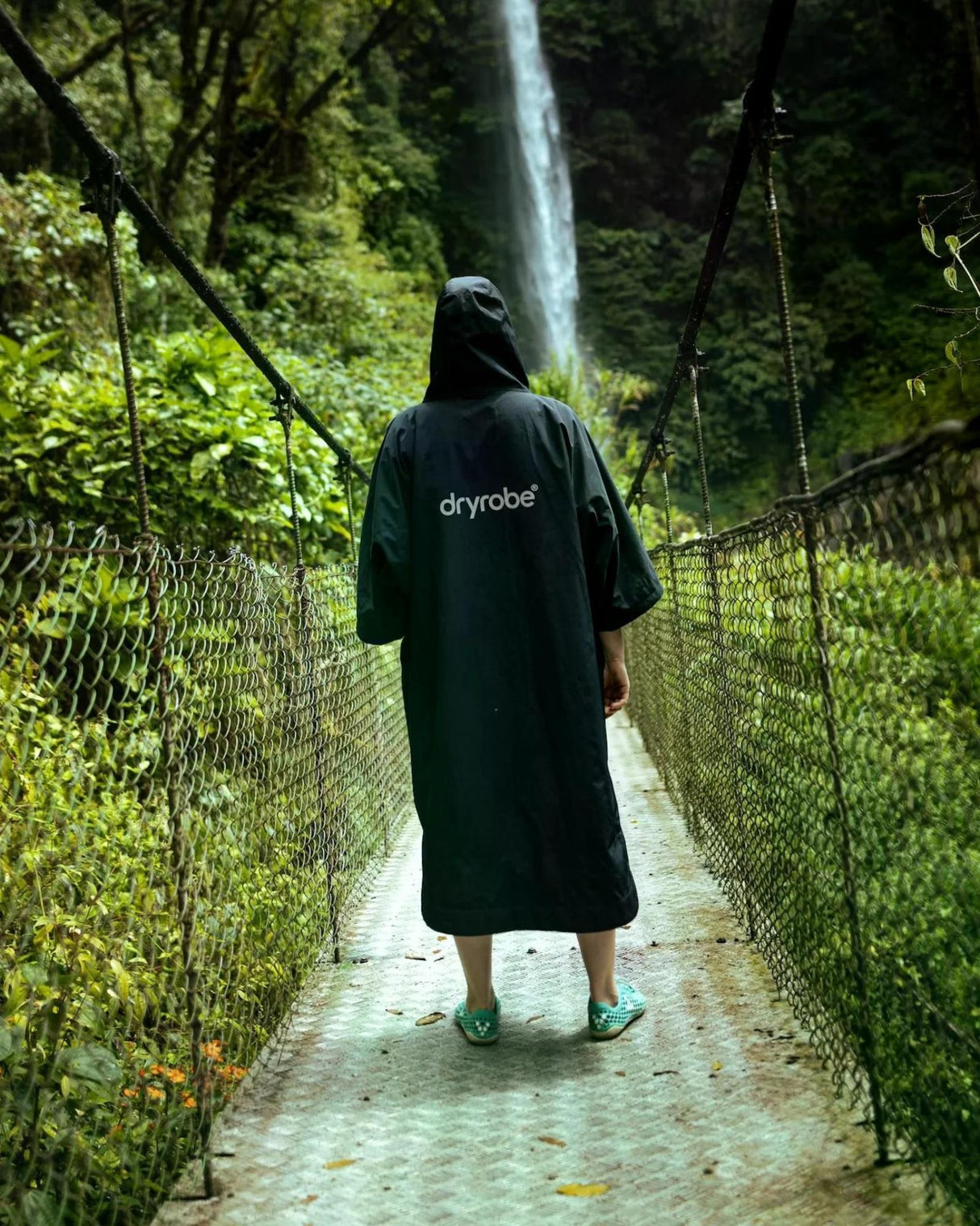 Dryrobe Tech-Lite Kurzarm in Schwarz, Rückenansicht, Person trägt Umhang in grüner Natur