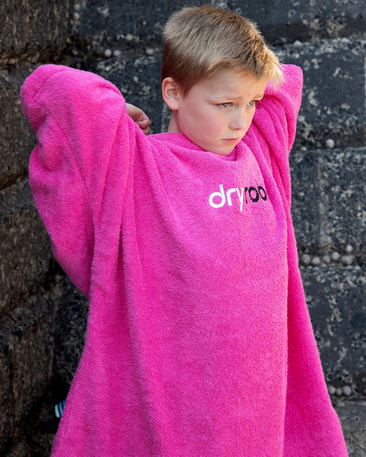 Dryrobe Handtuchmantel Bio Kids in Pink mit weichem Frottee, Kind trägt Mantel mit erhobenen Armen, Frontansicht