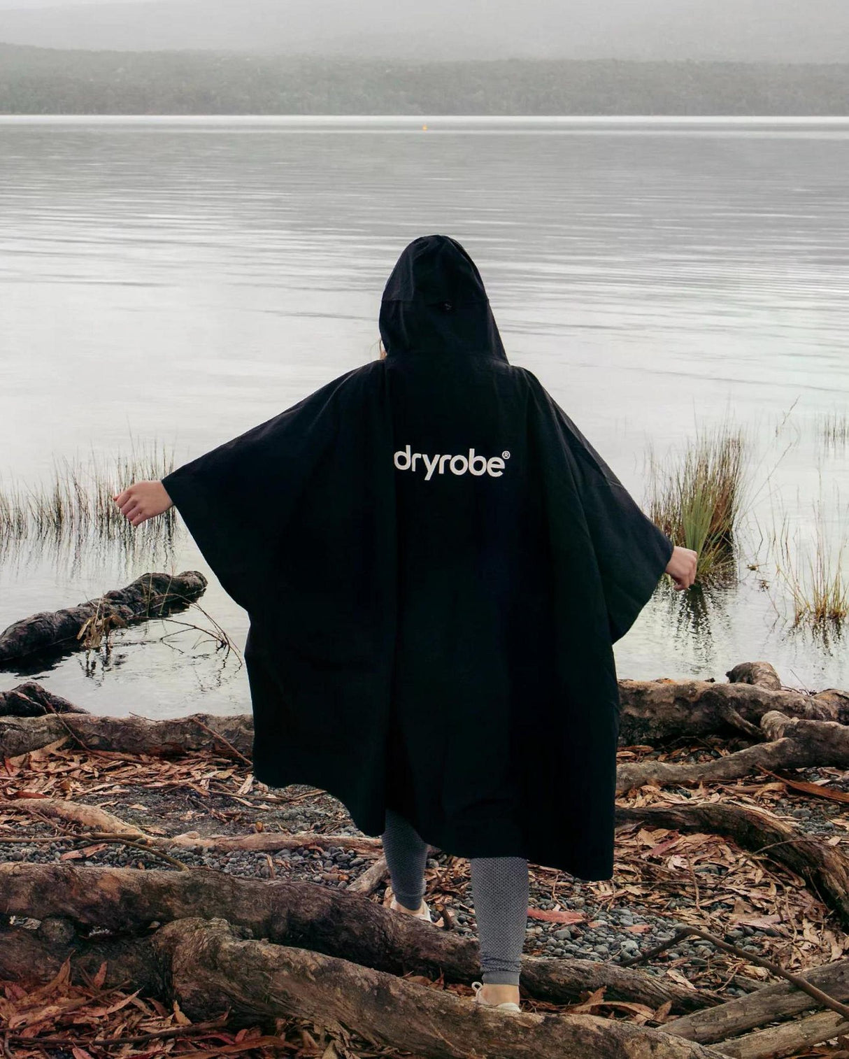 Dryrobe Regen-Poncho schwarz wasserdicht, Person von hinten am See tragend