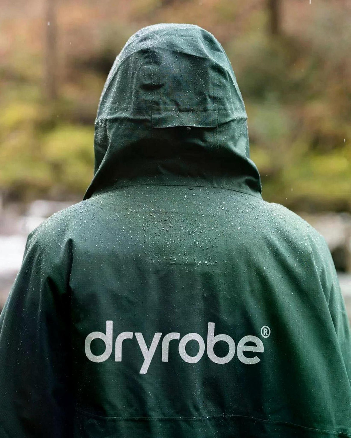 Dryrobe Regen-Poncho wasserdicht in Dunkelgrün, Rückansicht mit Kapuze, Regentropfen sichtbar, Markenlogo auf Rücken