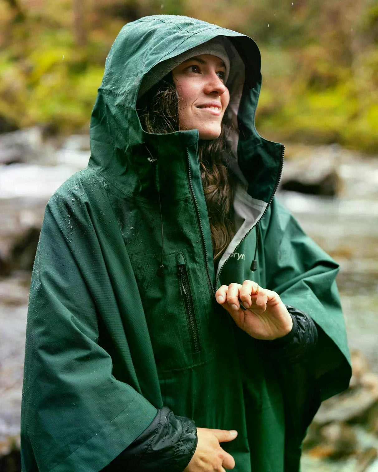 Dryrobe Regen-Poncho in Dunkelgrün, wasserdicht, mit großer Kapuze, getragen von Frau in Außenumgebung