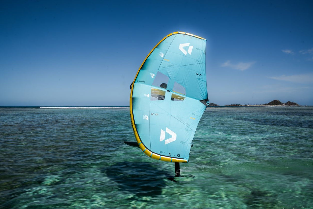 Duotone Unit D/LAB 2027 Kiteboard in hellblau mit gelbem Rahmen, im Wasser von vorne fotografiert