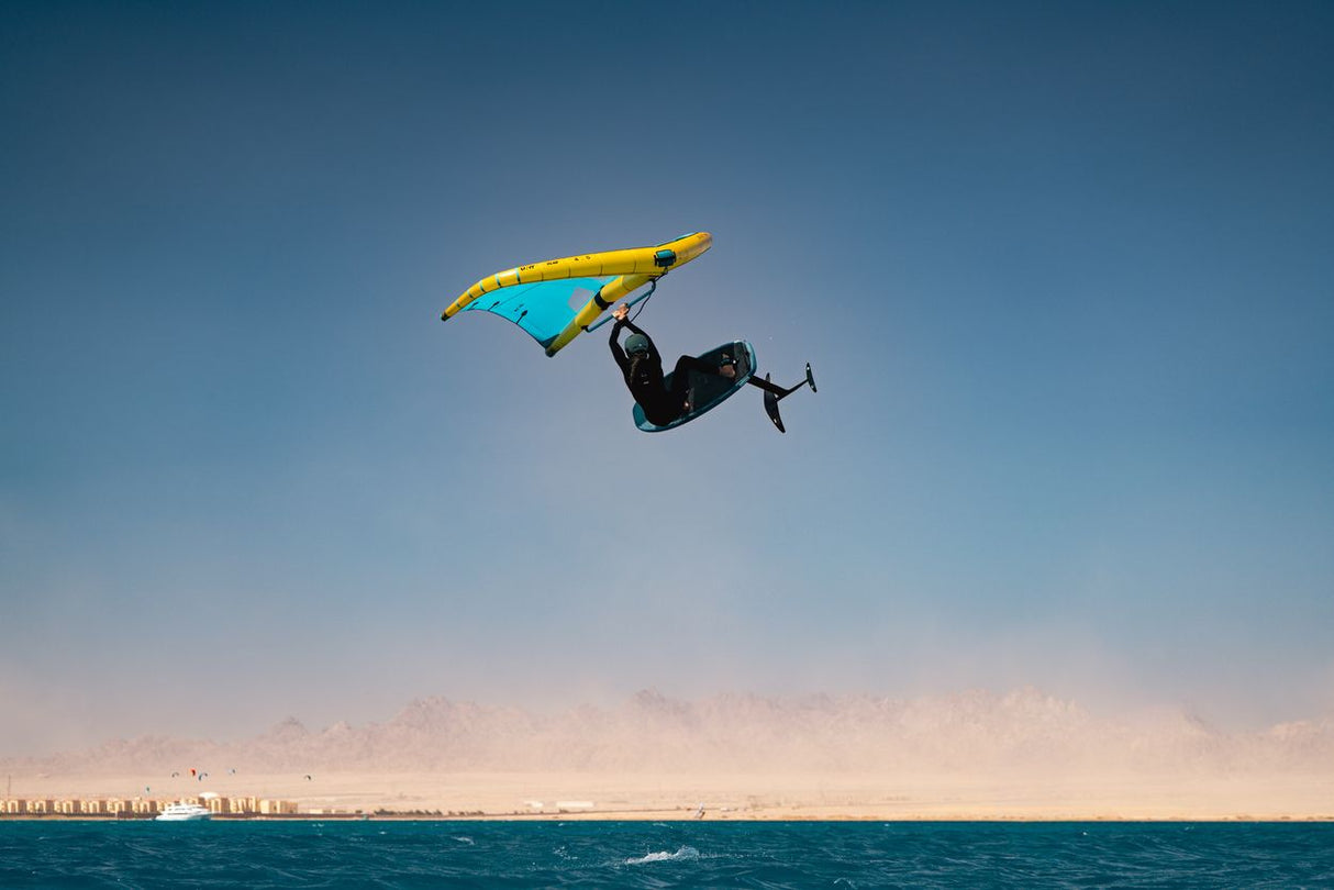 Duotone Unit D/LAB 2027 Kiteboard Gelb-Blau in Aktion über dem Wasser, Frontalansicht
