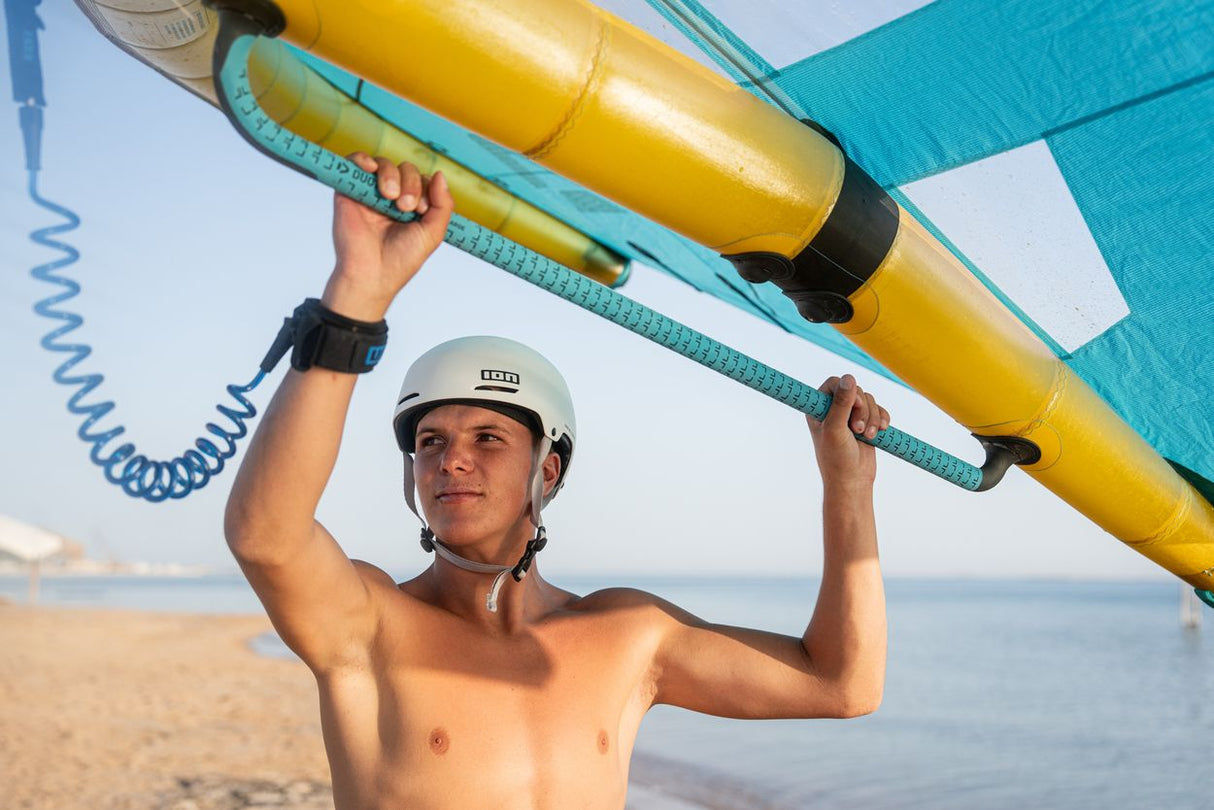 Duotone Unit D/LAB 2027 Kiteboard gelb-schwarz, Athlet trägt Board über Kopf am Strand, Frontalansicht