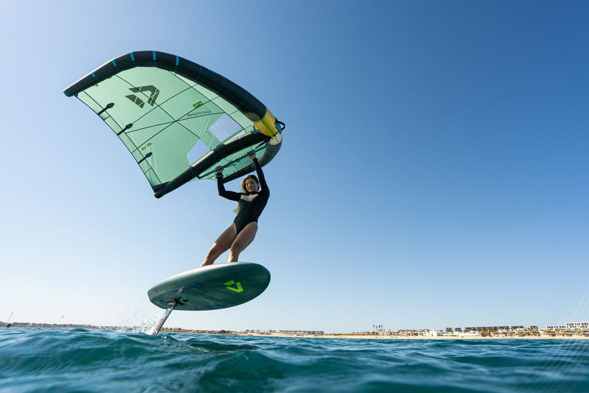 Duotone Unit SLS 2027 Kitesegel grün-schwarz mit Board im Wasser, Frontalansicht beim Kitesurfen