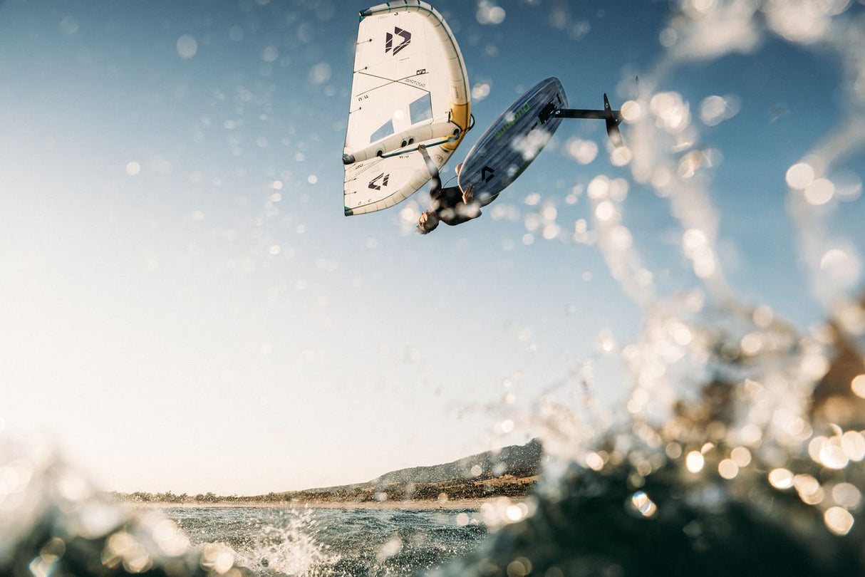 Duotone Unit SLS 2027 Kiteboard weiß-schwarz in Sprungaction über Wasser von unten fotografiert