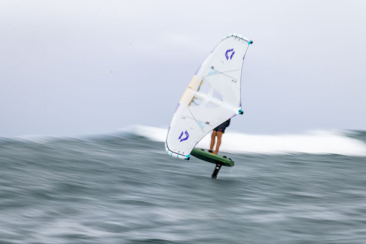Duotone Unit SLS Concept Blue 2027 Kiteboard mit weißem Segel und blauem Logo auf Welle, Seitenansicht