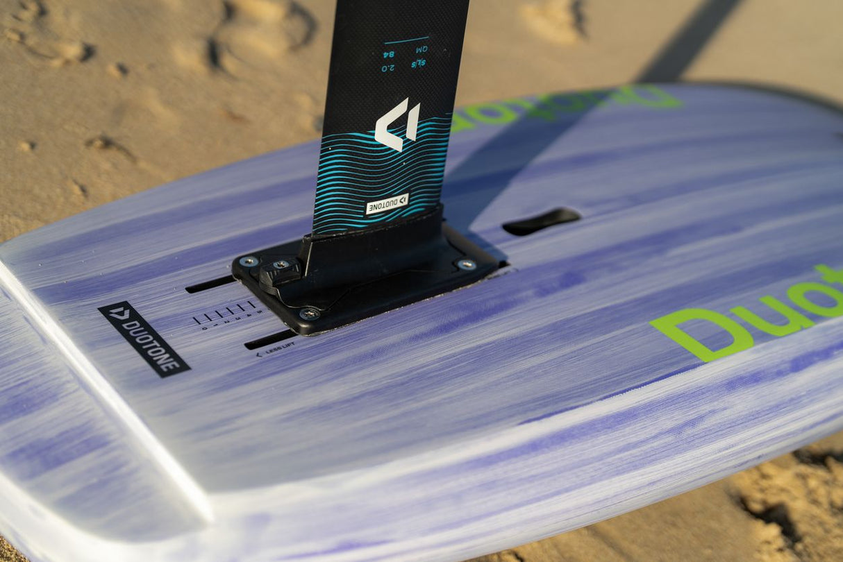 Duotone Sky Style 2027 Kiteboard mit blau-weißem Duotone-Design und schwarzer Finne, Nahaufnahme am Strand