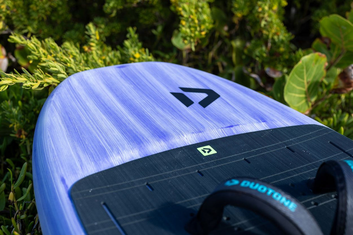 Duotone Sky Style 2027 Kiteboard mit blau-weißem Duotone-Design, schwarzem Streifen und Griffen, Draufsicht auf Gras