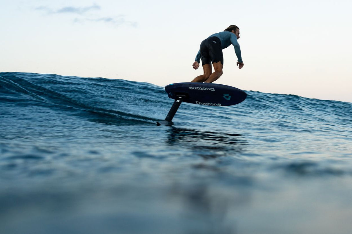 Duotone Crush SLS 2027 Foil-Board in Schwarz, Fahrer auf Welle im Meer, Seitenansicht
