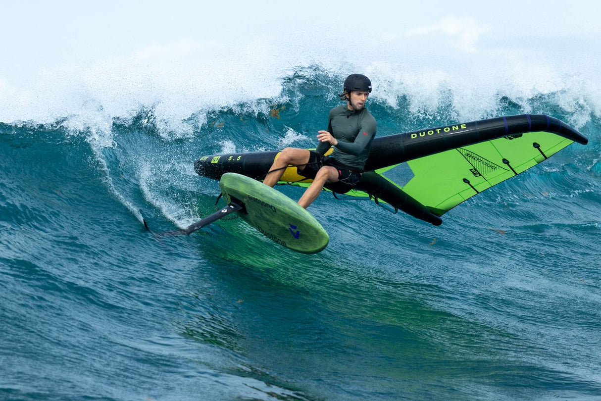 Duotone Trace SLS 2027 Kiteboard in Neongrün und Schwarz, Kitesurfer auf Welle in Aktion