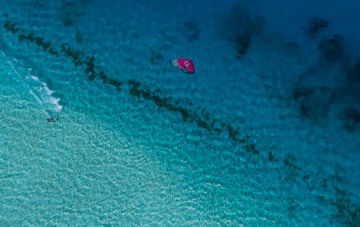 Duotone Select Concept Blue 2027 Kiteboard in Pink-Magenta, Draufsicht über türkisblauem Wasser
