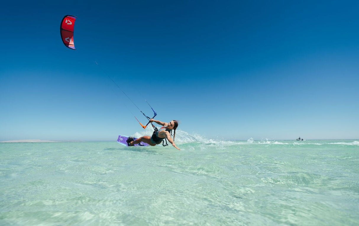 Duotone Soleil Concept Blue 2027 Kitesegel rot, Kitesurfer in türkisblauem Wasser, Frontalansicht