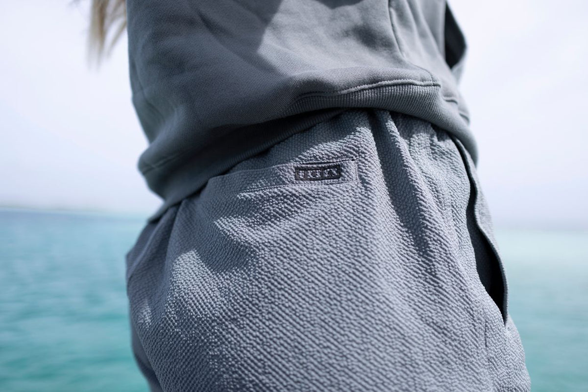 ION Tally 2.5 Boardshorts Damen in Grau, getragen am Meer, Detailansicht der Hüfte und Oberschenkel