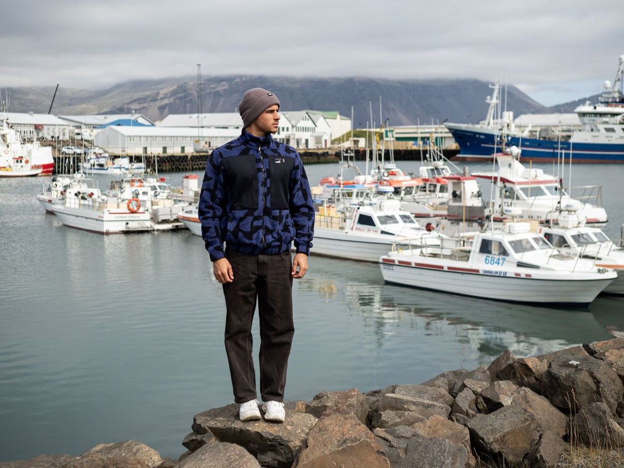 ION HD Fleece Jacke 2026 in Dunkelblau, getragen von Person am Hafen mit Booten im Hintergrund