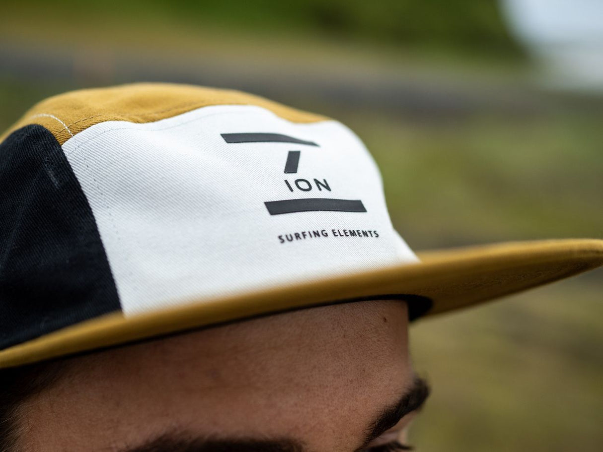 ION Cap 5 Panel 2024 in Weiß und Schwarz mit Logo, 5-Panel-Kappe, Seitenansicht auf Surfboard