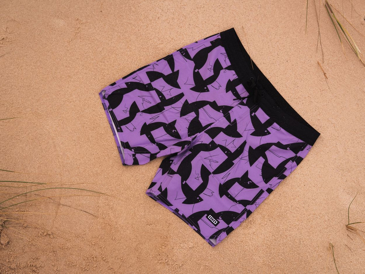 ION Boardshorts AOP 2026 in Violett mit schwarzem Allover-Print, Draufsicht am Strand