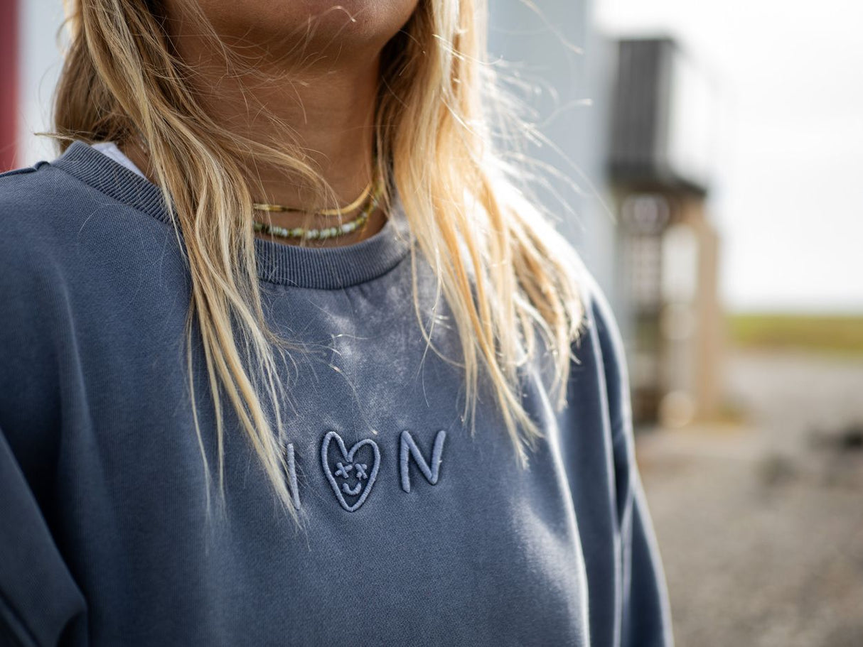 ION Sweater Mood 2026 in Marineblau mit Herz-Logo, Detailaufnahme auf Person getragen