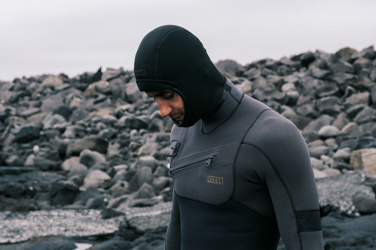 ION Neo Top Hooded Vest 2/1 dunkelblau mit Kapuze, Neopren-Oberteil, seitliche Ansicht an felsiger Küste