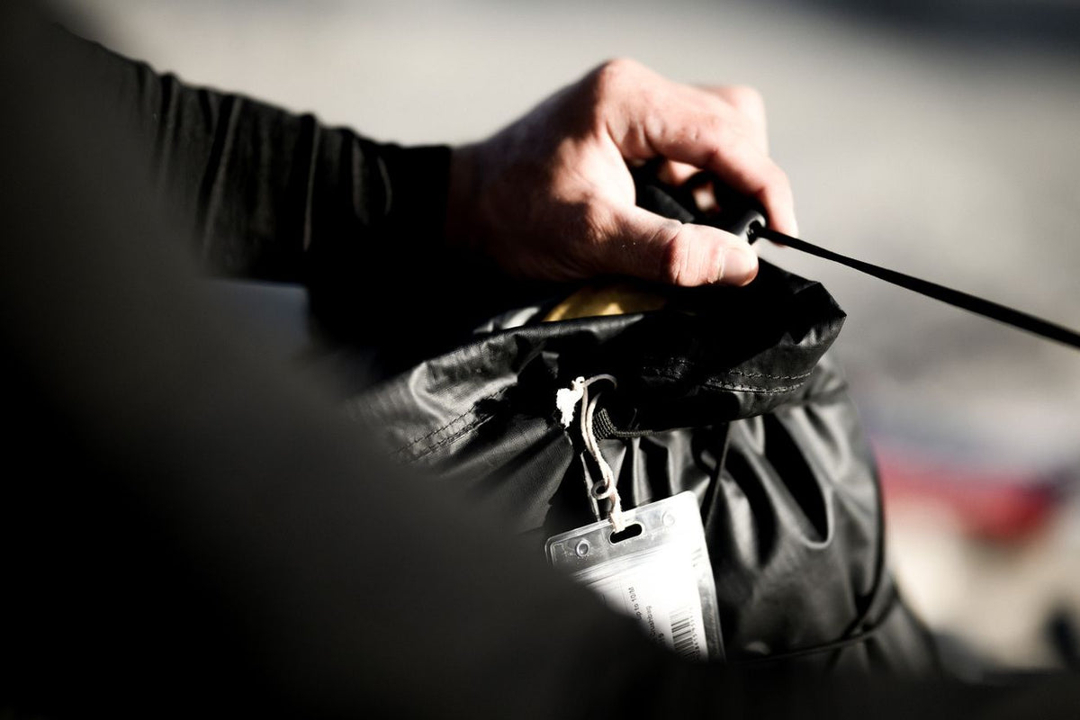 ION Kite Crushbag 2026 schwarz, Transporttasche mit Zugband, in Hand gehalten am Strand