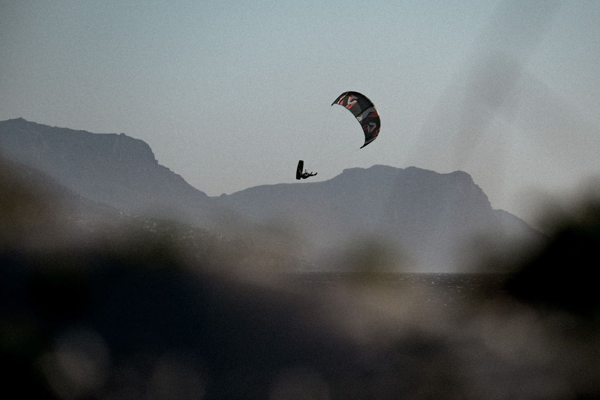 ION Core Long Sicherheitsleine 2026, schwarze Kitesurfing-Leine in Aktion über Wasser mit Bergkulisse