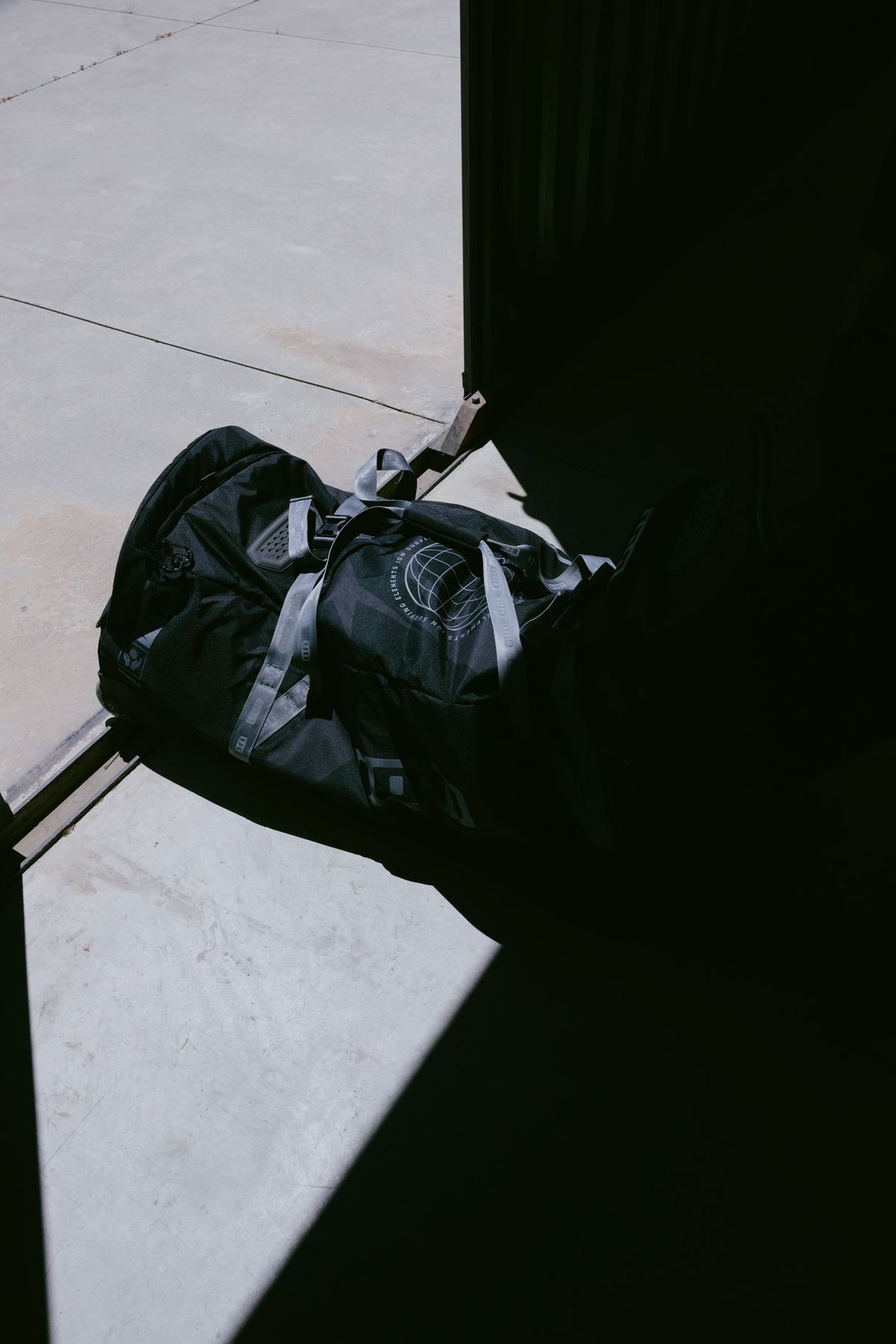 ION Gearbag Tec Golf 2026 Tasche in Schwarz-Grau, Draufsicht auf Betonuntergrund, Transporttasche mit Griffen und Verschlüssen