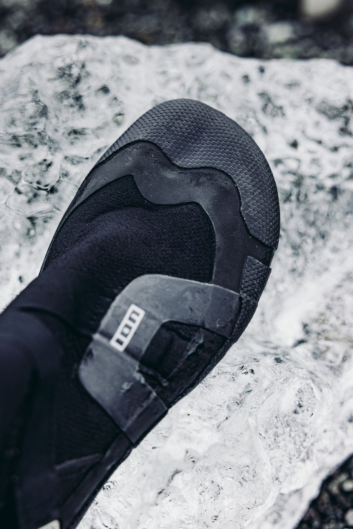 ION Ballistic Boots 3/2 schwarzer Neoprenanzug-Schuh mit geteilter Sohle, von oben auf Felsen fotografiert