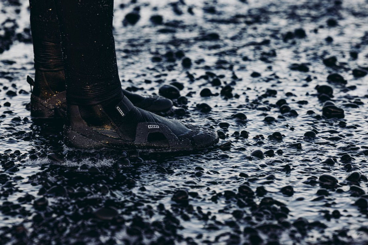 ION Ballistic Shoes 2.5 schwarz im Wasser, Seitenansicht mit Kieselsteinen, wasserfest