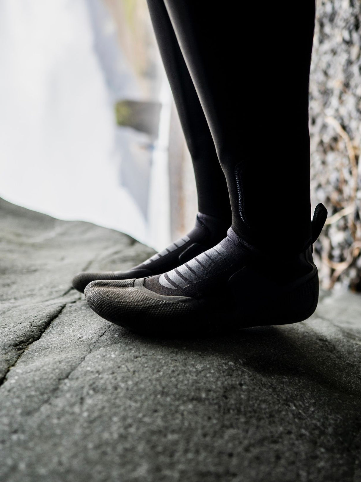 ION Plasma Boots 3/2 Internal Split schwarz, getragen auf Stein, Detailansicht Sohle und Ferse