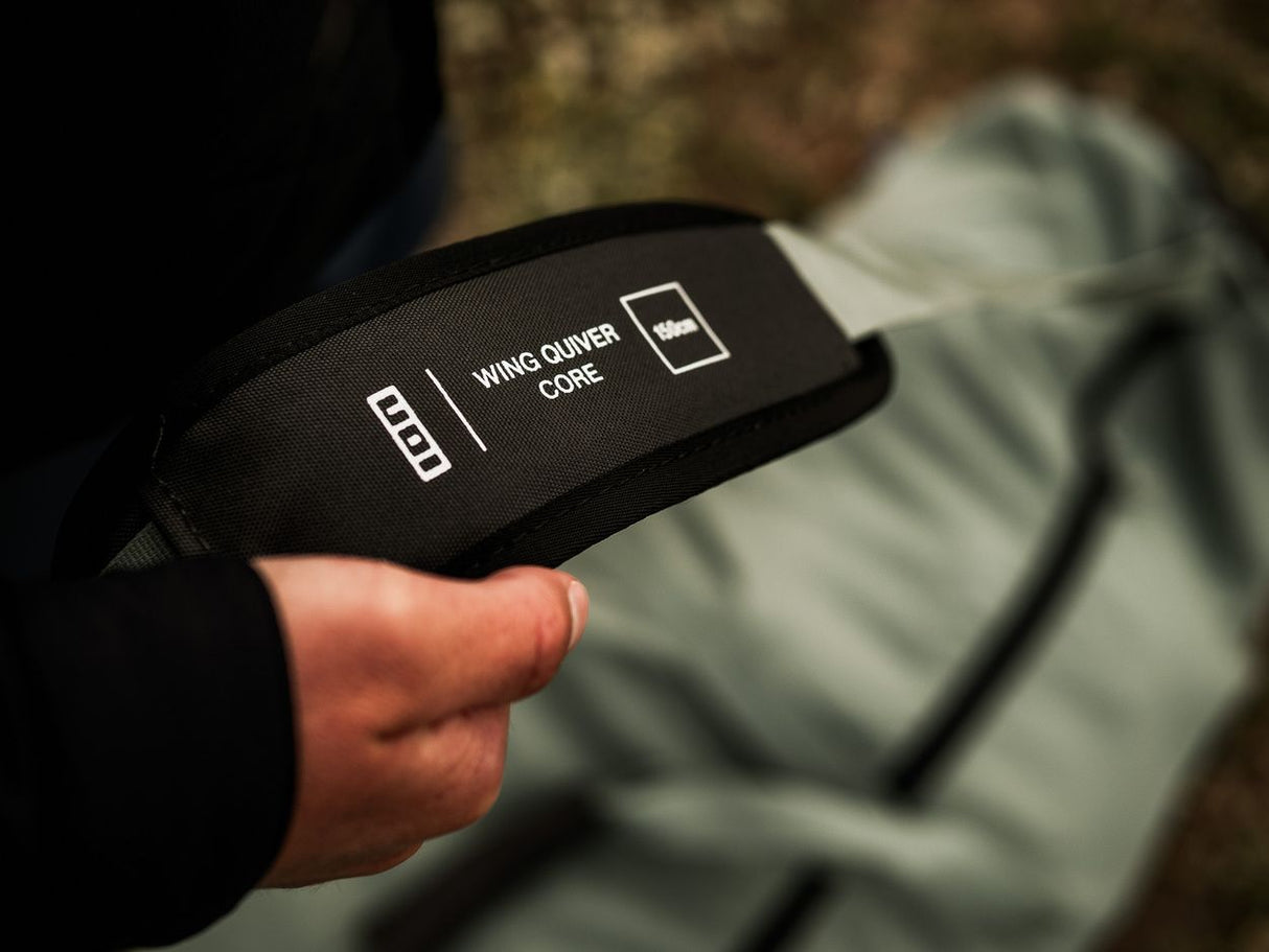 ION Wing Quiverbag Core 2026 schwarze Transporttasche mit Schultergurt, in Hand gehalten, Detailansicht des Logos